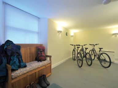 A room with wooden bench with jackets and boots and bicycles against a wall at Low Croft Cottage in Grasmere