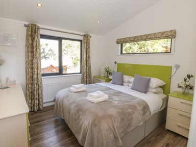 A bedroom with a double bed two bedside tables and a dresser at Windermere Lodge in Bowness-On-Windermere