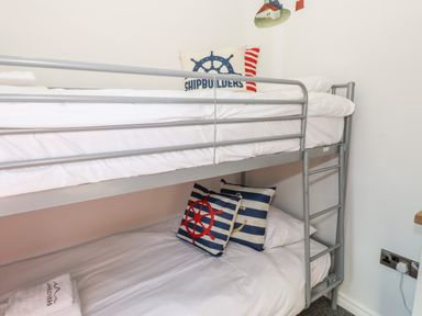 A bedroom with a metal bunk bed with nautical themed pillows at Windermere Lodge in Bowness-On-Windermere