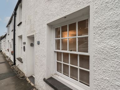 White textured exterior wall with a window and a door numbered 3 on a row of similar houses