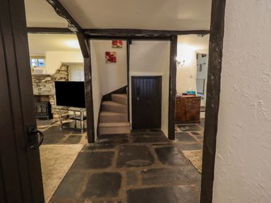 A hallway with a small staircase carpeted leading up and a small black door beneath the stairs at Birchcroft in Ambleside