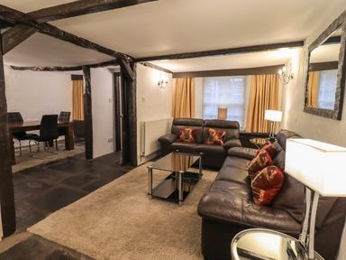 A living room with two leather sofas a glass coffee table and a dining area with a table and chairs at Birchcroft in Ambleside