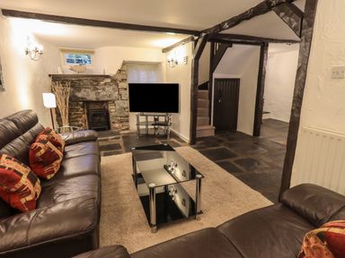 A living room with leather sofas a glass coffee table a stone fireplace and a television at Birchcroft in Ambleside