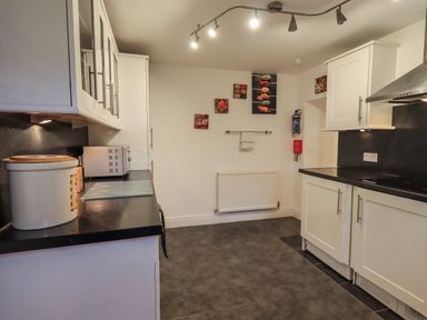 A kitchen with white cabinets black countertops microwave and decorative pictures on the wall at Birchcroft Ambleside
