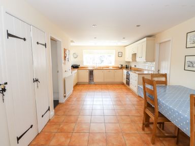A kitchen with wooden chairs and table with polka dot tablecloth and white cabinets at Robin Cottage in Troutbeck