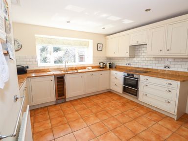 A kitchen with cream cabinets and orange tiled floor at Robin Cottage in Troutbeck