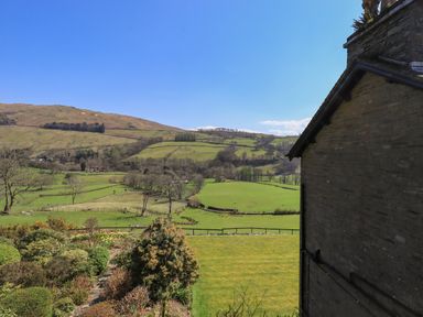 A garden and fields with trees and hills under a clear sky at Boxwood Cottage in Troutbeck