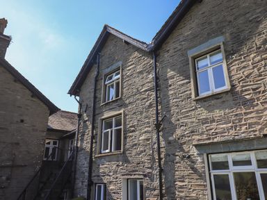 Exterior view of a stone building with multiple windows and a staircase at Boxwood Cottage in Troutbeck