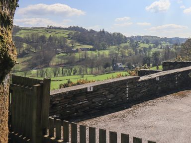 A stone wall and wooden gate overlooking green fields and rural hills at Boxwood Cottage in Troutbeck
