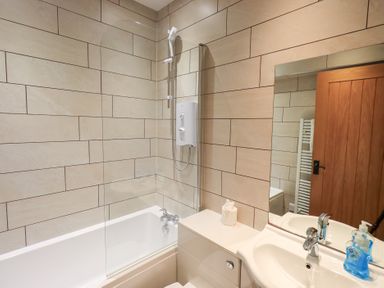 A bathroom with a shower, bathtub, and sink at Boxwood Cottage in Troutbeck
