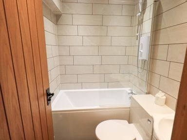 A bathroom with a bathtub and toilet at Boxwood Cottage in Troutbeck