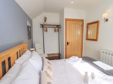 A bedroom with a bed and shelving at Boxwood Cottage in Troutbeck