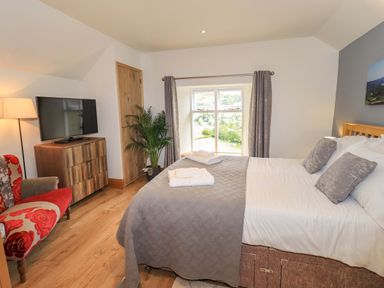 A bedroom with a bed and television at Boxwood Cottage Troutbeck