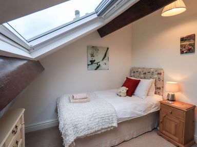 A bedroom with a single bed bedside table lamp and skylight window at Stablemans Cottage at Stepping Stones in Ambleside