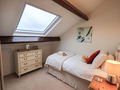 A bedroom with a single bed bedside table lamp chest of drawers and a skylight window at Stablemans Cottage at Stepping Stones Ambleside