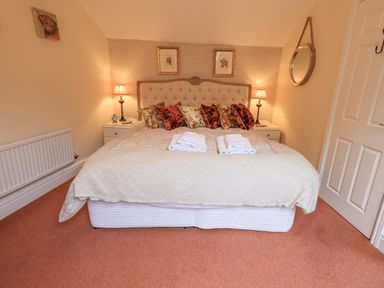 A bedroom with a double bed bedside tables lamps and a round wall mirror at Ghyll Heights in Ambleside