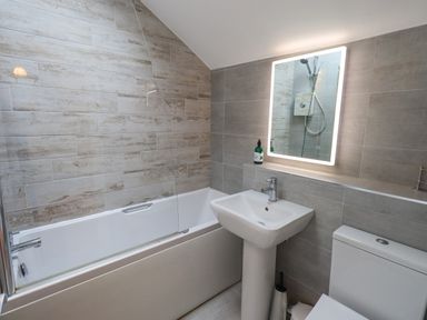 A bathroom with a bathtub a sink a toilet and an illuminated mirror at Ghyll Heights Ambleside