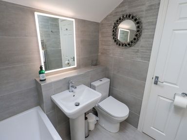 A bathroom with a sink toilet bathtub and two mirrors at Ghyll Heights Ambleside