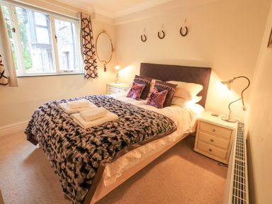 A bedroom with a double bed with towels on a blanket and bedside tables with lamps at Ghyll Heights in Ambleside