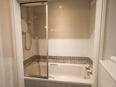 A bathroom with a bathtub shower and glass shower screen at Ghyll Heights in Ambleside
