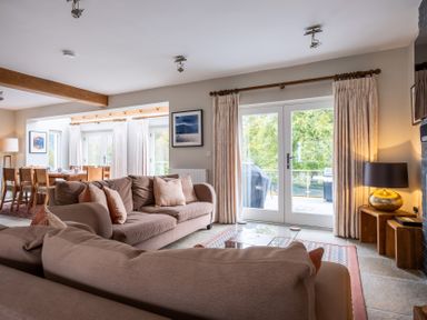 A living room with a sofa, dining area and large windows at Goody Raise in Grasmere