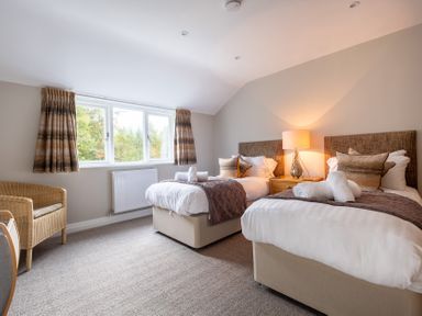 A bedroom with two beds and a chair at Goody Raise in Grasmere