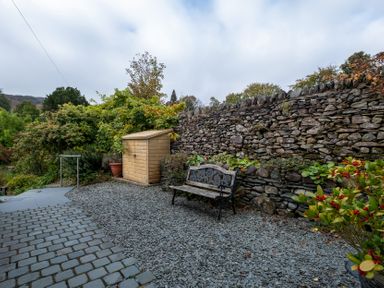 A garden with a bench and a shed at Goody Raise in Grasmere