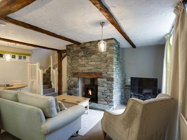 A living room with sofas a stone fireplace and a TV at Acorn Cottage in Grasmere