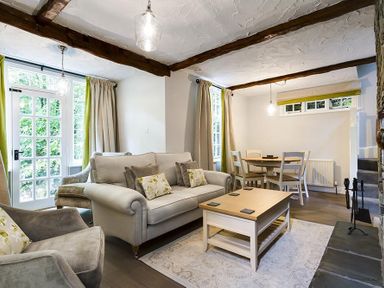 A living room with a sofa armchairs coffee table dining table and chairs at Acorn Cottage in Grasmere