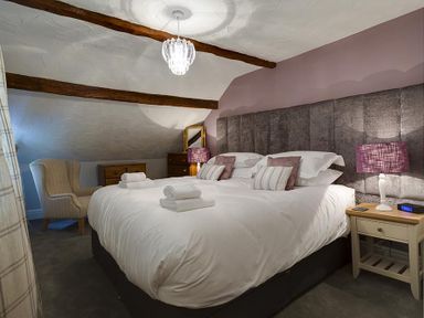 A bedroom with a double bed bedside tables lamps and an armchair at Acorn Cottage in Grasmere