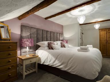 A bedroom with a double bed bedside tables lamps wardrobe and chest of drawers at Acorn Cottage in Grasmere