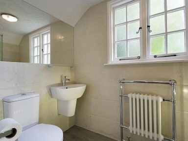 A bathroom with a toilet sink radiator and a window at Acorn Cottage in Grasmere
