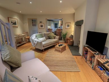 A living room with two sofas a wooden crate coffee table a television on wooden crates and an open doorway leading to a kitchen at Wainwright Cottage in Ambleside