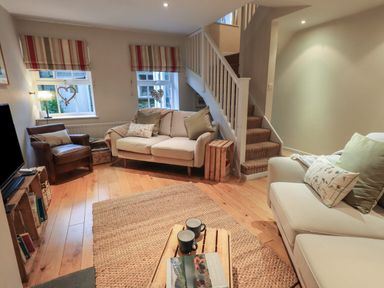 A living room with sofas a chair a wooden coffee table and stairs at Wainwright Cottage in Ambleside