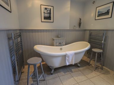 A bathroom with a freestanding bathtub stools and towel racks at Wainwright Cottage in Ambleside