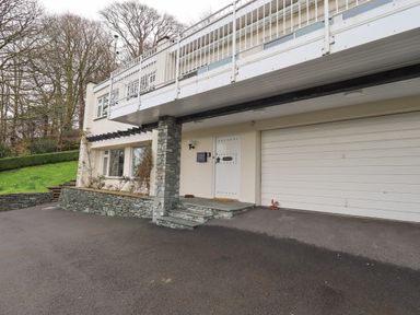 The exterior of a two-story house with a white front door a double garage door stone pillar and driveway at Tanna Hill in Bowness