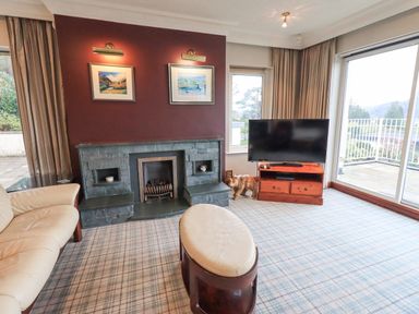 A living room with a fireplace television and a sofa at Tanna Hill in Bowness