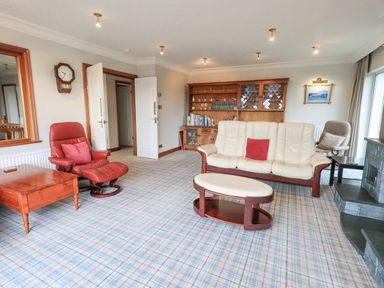 A living room with sofas a wooden cabinet and a fireplace at Tanna Hill in Bowness