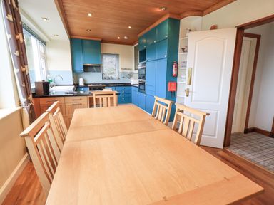 A kitchen with blue cabinets and wooden dining table with chairs at Tanna Hill in Bowness