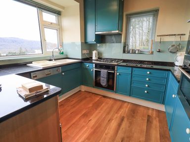 A kitchen with blue cabinets wooden floor and large windows at Tanna Hill in Bowness