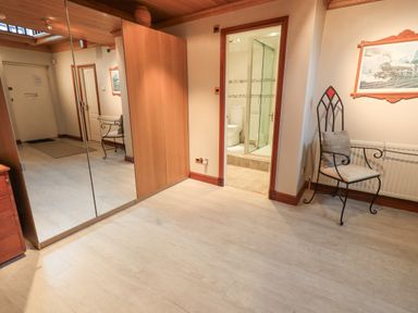 A hallway with a mirrored wardrobe a chair a door leading to a bathroom and a painting on the wall at Tanna Hill in Bowness