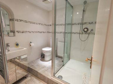 A bathroom with a shower enclosure toilet sink and mirror at Tanna Hill in Bowness