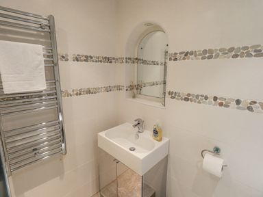 A bathroom with a sink a mirror towel rail and a toilet paper holder at Tanna Hill in Bowness