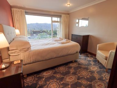 A bedroom with a bed near a large window showing a mountain view at Tanna Hill in Bowness