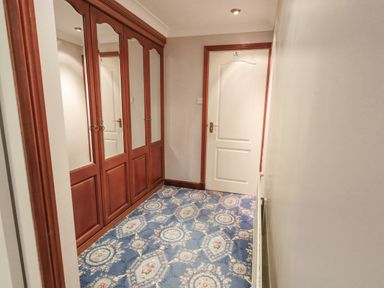 A hallway with mirrored wooden wardrobes and a white door with brown trim on a blue patterned carpet at Tanna Hill in Bowness