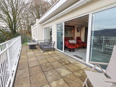 A patio with outdoor chairs and a table outside a room with sliding glass doors at Tanna Hill in Bowness