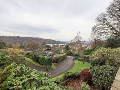 A residential neighborhood with houses trees shrubs and hills in the background at Tanna Hill in Bowness