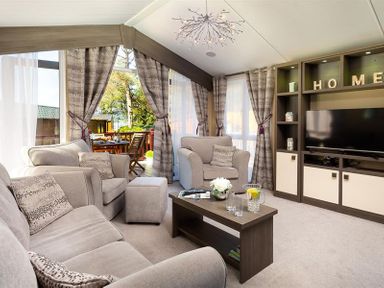 A living room with a sofa armchairs coffee table and television at Lancashire Rose in Ambleside