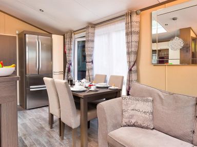 A dining area with a table set for breakfast next to a sofa and a refrigerator in a living space at Lancashire Rose Ambleside
