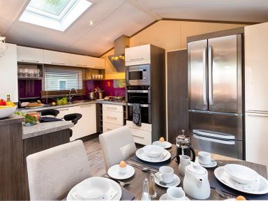 A kitchen and dining area with a table set for breakfast and stainless steel appliances at Lancashire Rose in Ambleside